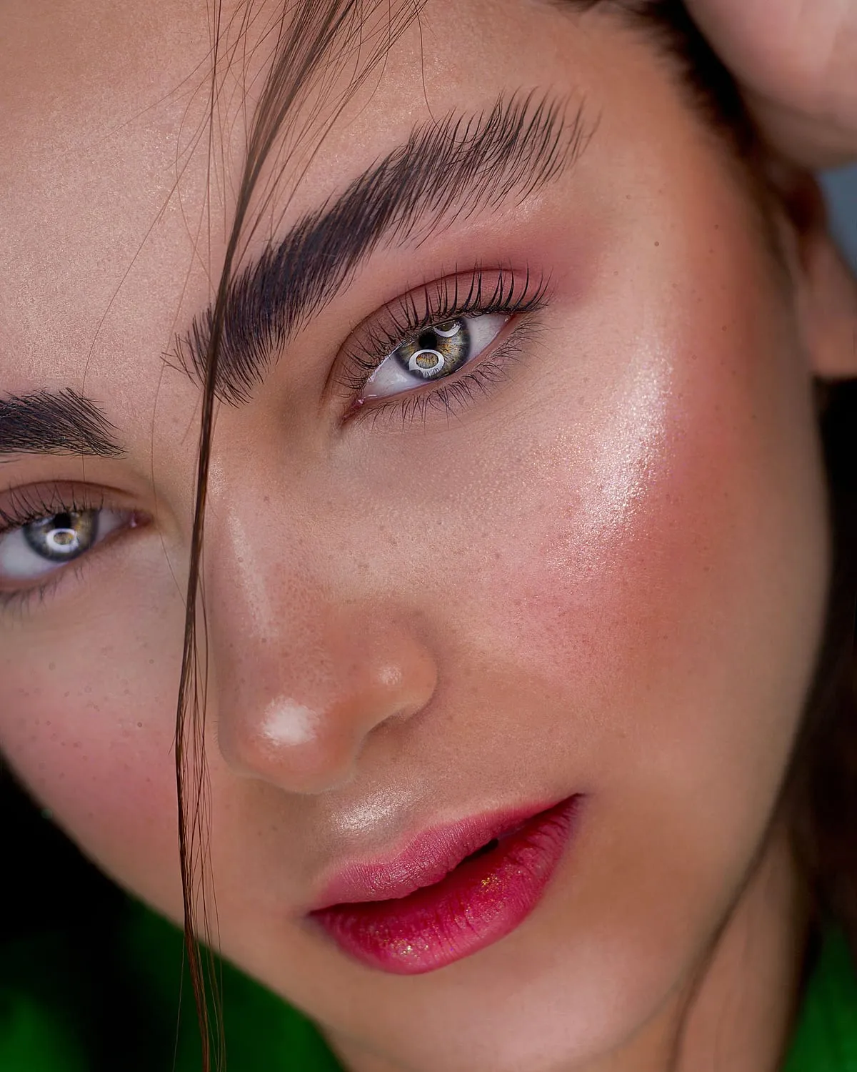 Woman with dewy skin, brushed-up brows, soft pink blush and glossy lips in a clean girl makeup look
