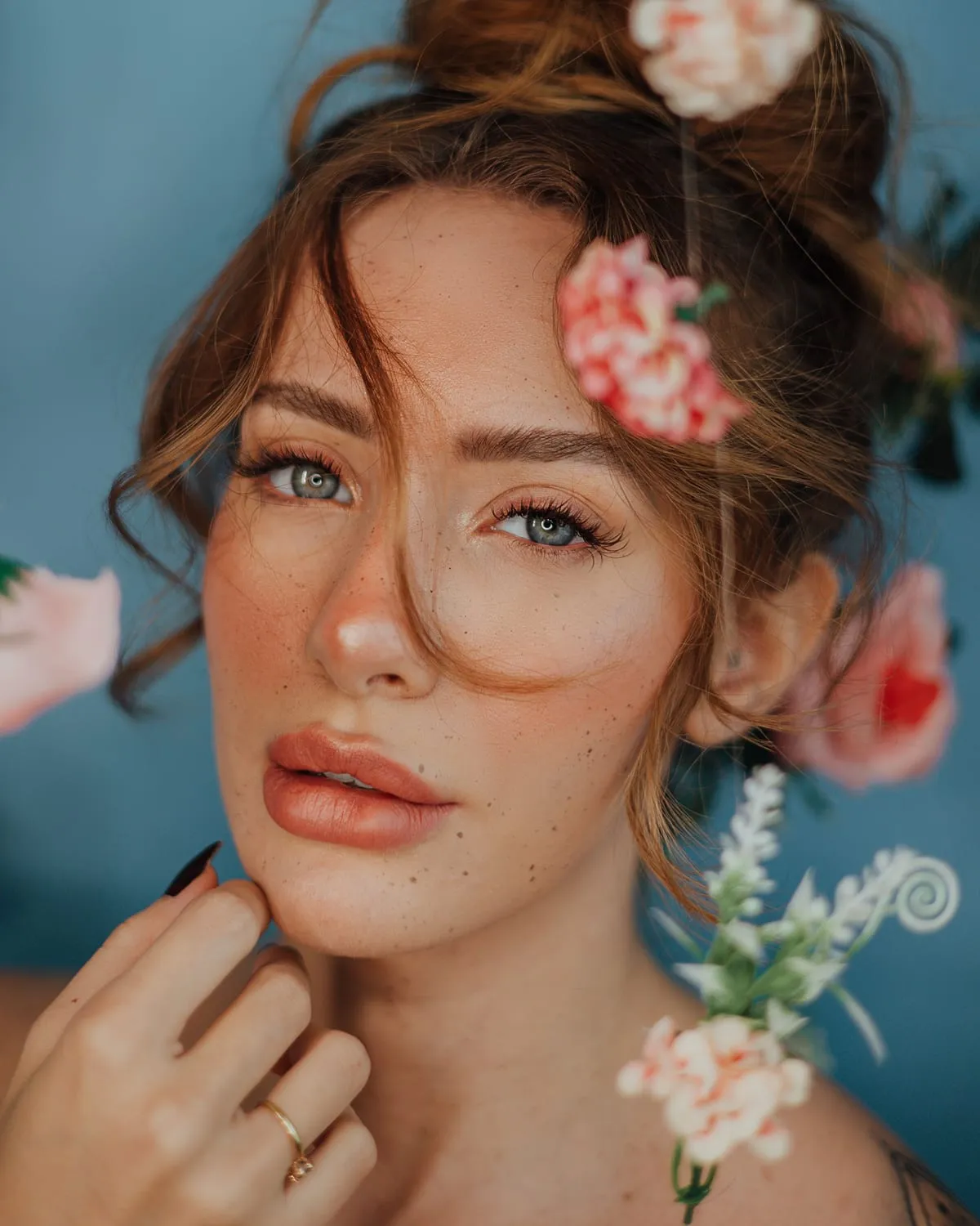 Woman with cottagecore makeup: freckles, rosy cheeks, soft lips and flowers in her hair