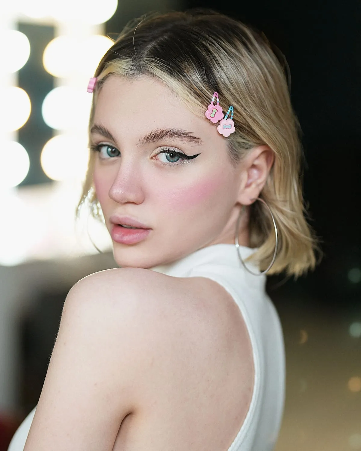 Woman with e-girl makeup: pink blush across the cheeks and nose, winged liner and hair clips