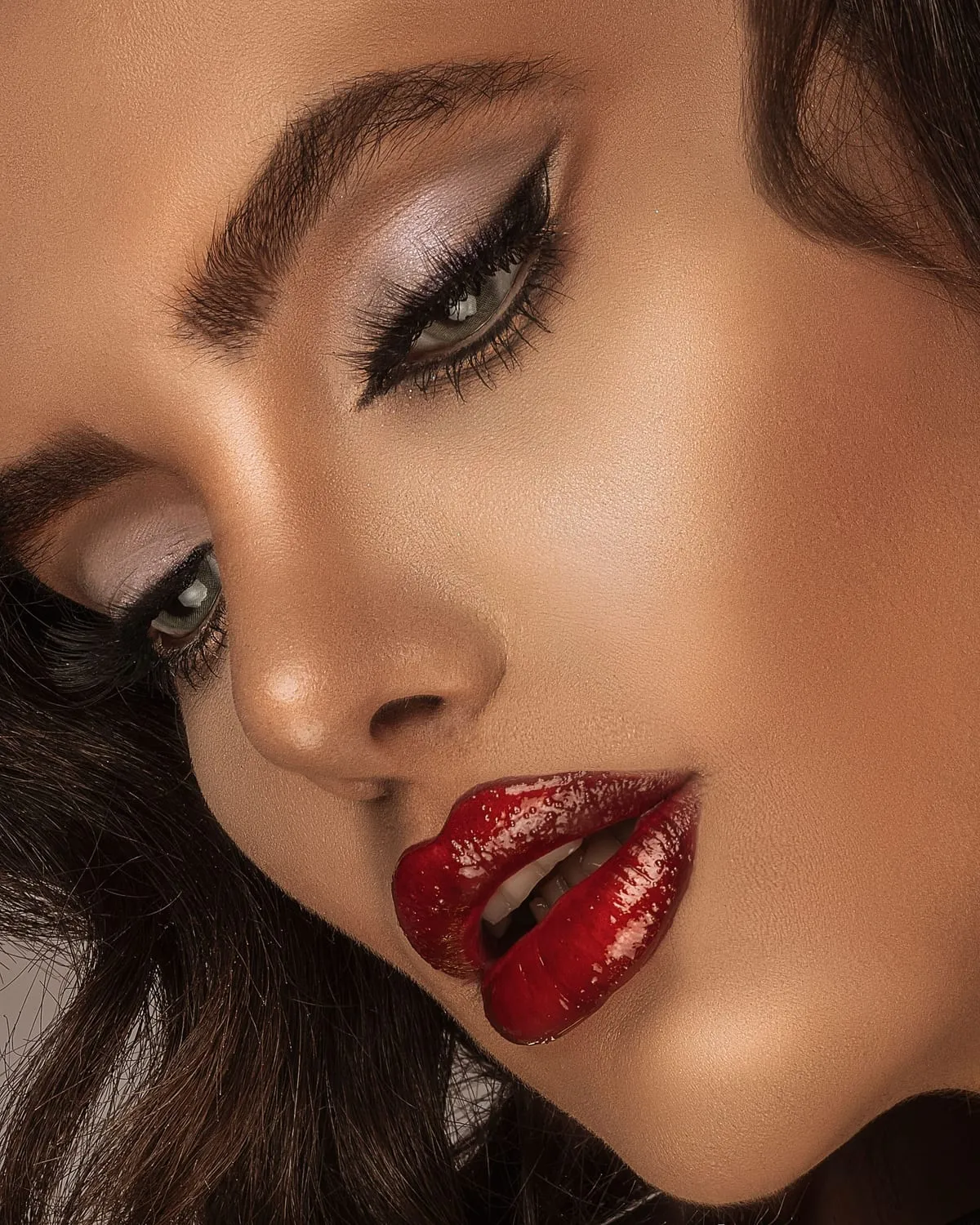 Woman in full glam makeup with smoky winged eyes, sculpted cheeks and glossy red lips